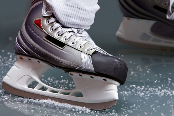 نمای نزدیک از اسکیت روی پای بازیکن در حین هاکی روی یخ