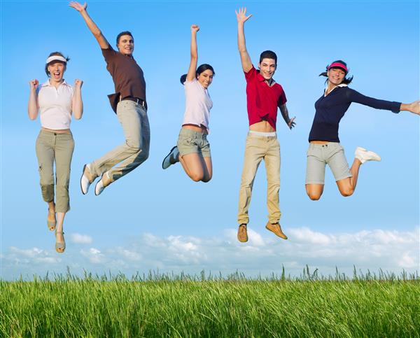 گروه شاد جوانان پرش در چمنزار آسمان آبی در فضای باز تصویر عکس