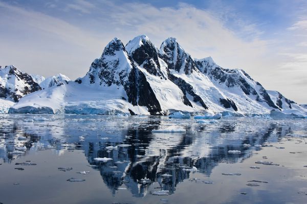 کوه های پوشیده از برف زیبا در مقابل آسمان آبی در قطب جنوب
