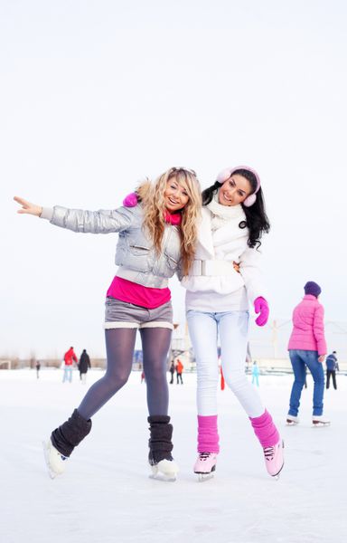 دو دختر زیبا که در یک روز گرم زمستانی در فضای باز اسکیت می کنند