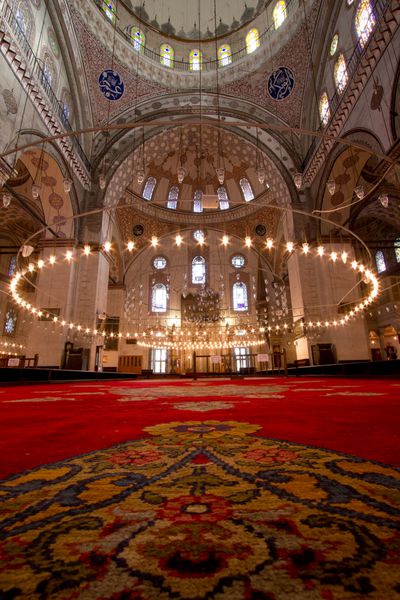 داخل مسجد استانبول با فرش قرمز در پیش زمینه تصویر با جزئیات زیاد مسجد و ستون های بزرگ