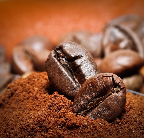 نمای نزدیک از دو دانه قهوه در پشته قهوه برشته شده دانه قهوه در پس زمینه ماکرو آسیاب شده قهوه قهوه برشته عربی - جزء نوشیدنی داغ
