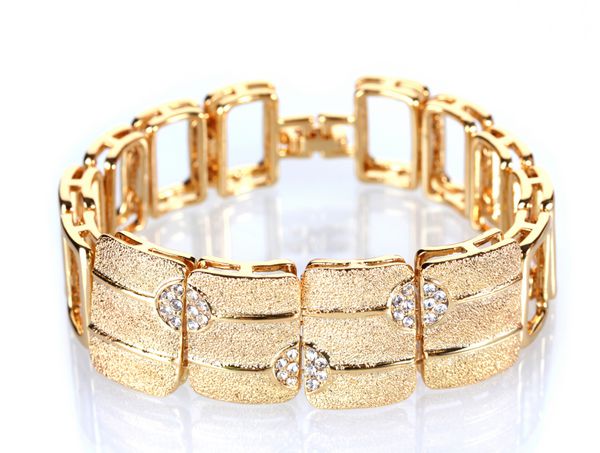 دستبند طلایی زیبا با سنگ های قیمتی جدا شده روی سفید