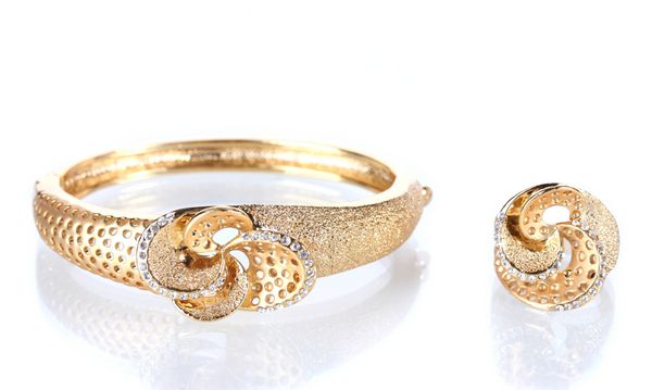 دستبند و انگشتر طلایی زیبا با سنگ های قیمتی جدا شده روی سفید
