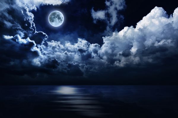 ماه کامل در آسمان شب بر روی آب مهتابی