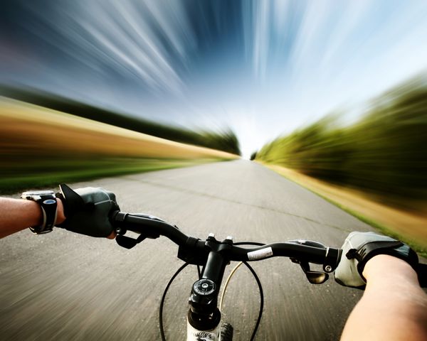 دوچرخه سواری در جاده آسفالته رانندگی می کند پس زمینه تار حرکت