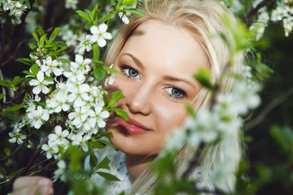 زن جوان سالم و زیبا با گل های بهاری