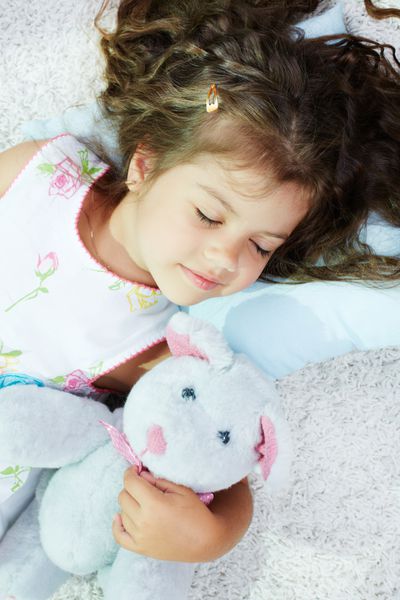 پرتره دختر دوست داشتنی که با خرس عروسکی خوابیده است