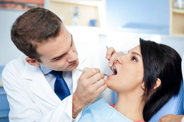 بیمار زن با دندانپزشک و دستیار - درمان دندانپزشکی
