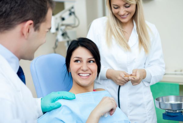 دندانپزشک مرد دستیار او و بیمار زن در مطب دندانپزشکی