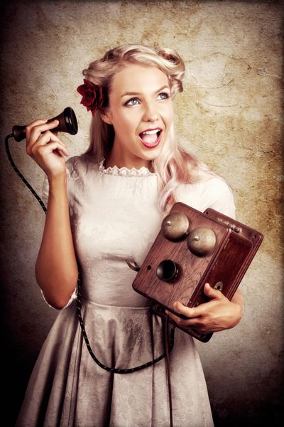 زن جوان شوکه شده که در حالی که به عنوان اپراتور تلفن مشغول به کار بود گوشی جعبه چوبی قدیمی را در دست دارد در یک مفهوم خبر خوب یا بد