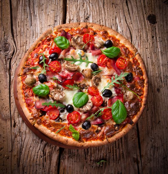 پیتزای خوشمزه ایتالیایی که روی میز چوبی سرو می شود