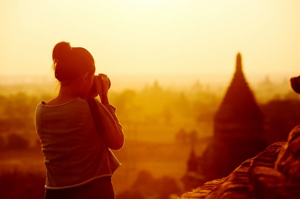 مسافر زن در حال عکاسی از معابد باگان میانمار آسیا در طلوع خورشید