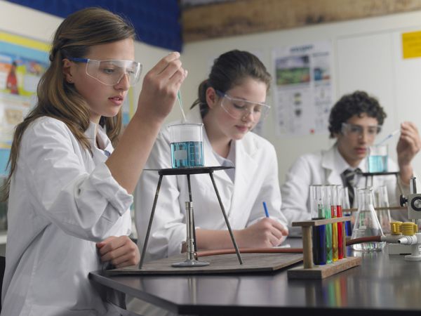 دانش آموزان نوجوان در حال انجام آزمایشات در کلاس شیمی