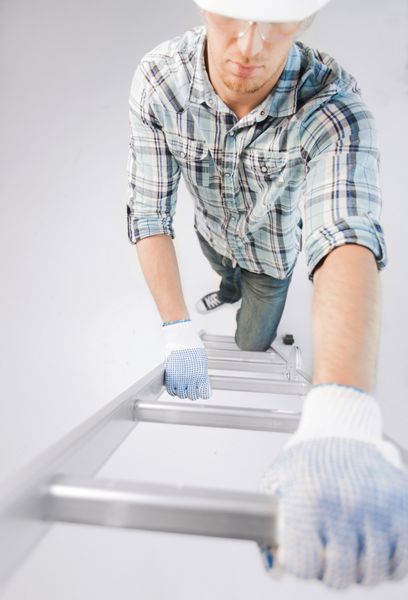 طراحی داخلی و مفهوم بازسازی خانه - مردی با کلاه ایمنی و دستکش در حال بالا رفتن از نردبان