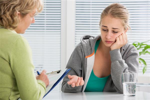 دختر نوجوان مبتلا به افسردگی در گفتگو با درمانگر یا روانشناس
