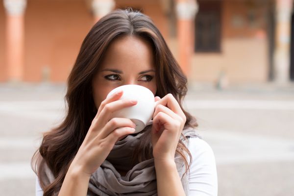 دختر زیبای شاد در حال نوشیدن یک فنجان قهوه - پرتره در فضای باز