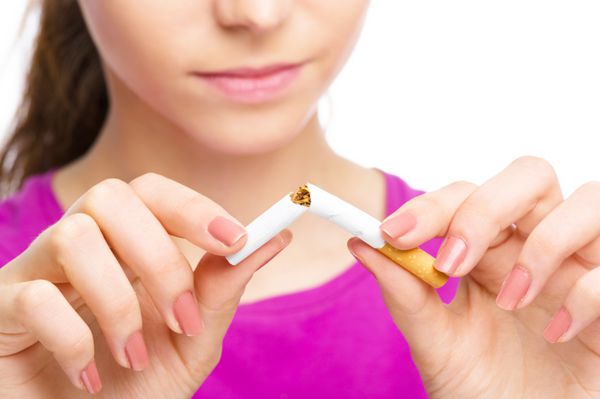 زن جوان در حال شکستن سیگار مفهوم ترک سیگار جدا شده روی سفید است