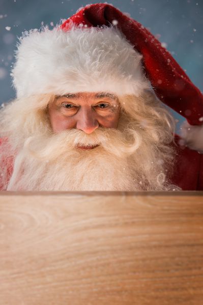 بابا نوئل به جعبه چوبی در فضای باز نگاه می کند نور از درون به صورتش می آید افتتاح مفهوم جادوی کریسمس