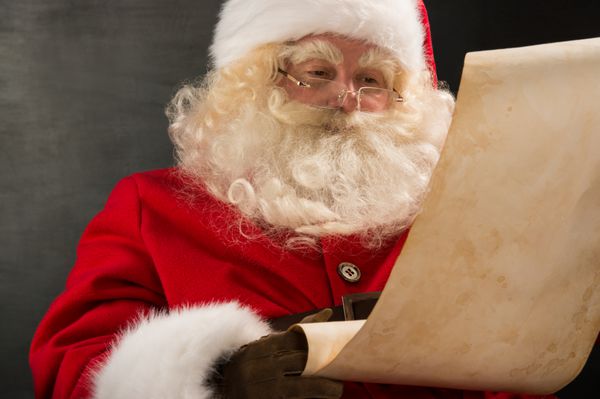 پرتره بابا نوئل در حال خواندن نامه بزرگ روی رول کاغذی قدیمی