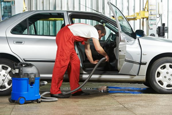 تم تمیز کردن خودرو مکانیک کابین خودرو را با جاروبرقی در گاراژ تعمیرگاه خودرو سوار می کند