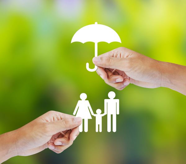 دستی که یک خانواده کاغذی و چتر در پس زمینه سبز در دست گرفته است