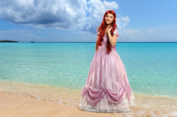 زن جوان زیبا با لباس پرنسس در کنار ساحل