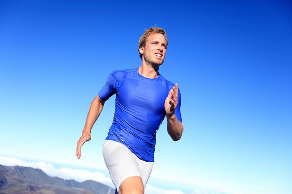 دونده ورزشکار در حال دویدن برای موفقیت تمرین دوندگان سرعت تناسب اندام مردانه در دوی سرعت با اراده و قدرت مرد خوش تیپ ورزشکار در حال تمرین در بیرون در آسمان آبی
