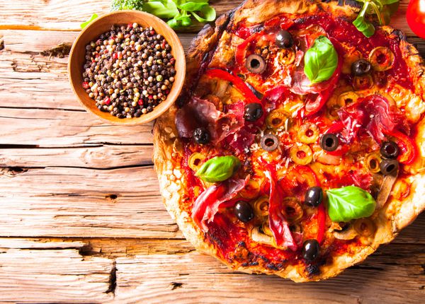 پیتزای تازه خوشمزه ایتالیایی که روی میز چوبی سرو می شود سبزیجات تازه روی میز چوبی
