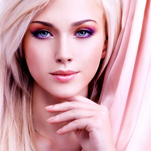 زن زیبا با ابریشم صورتی که صورتش را جدا شده روی سفید لمس می کند