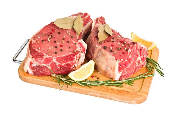 گوشت خام با ادویه در تخته چوبی جدا شده در پس زمینه سفید
