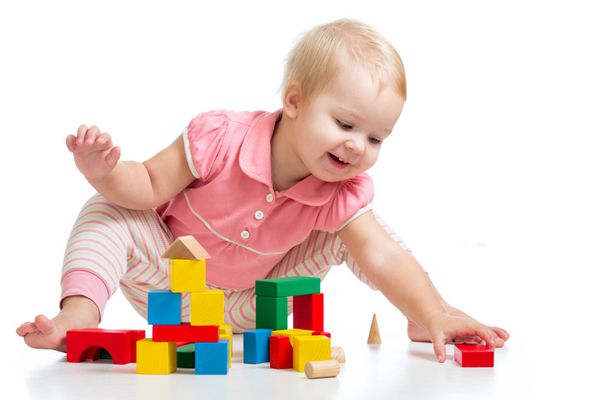 بچه خوشحال در حال بازی بلوک های اسباب بازی جدا شده در پس زمینه سفید