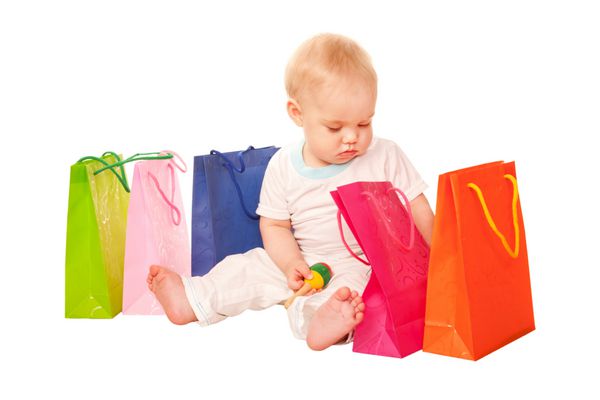 خرید نوزاد کودک شاد با کیسه های خرید نشسته و خرید را بررسی می کند جدا شده در زمینه سفید