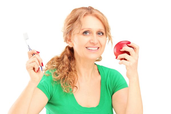 زن بالغ لبخند می زند سیب قرمز و مسواک جدا شده در زمینه سفید