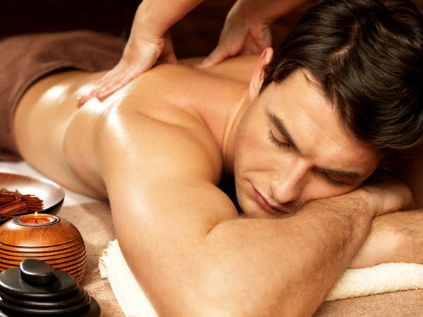 ماساژور در سالن اسپا روی بدن مرد ماساژ پشت انجام می دهد مفهوم درمان زیبایی
