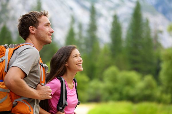 زوج - کوهنوردان فعال در حال پیاده روی با تماشای منظره جنگل کوهستانی در پارک ملی یوسمیتی کالیفرنیا ایالات متحده زوج خوشبخت چند نژادی در فضای باز زن جوان آسیایی و مرد قفقازی