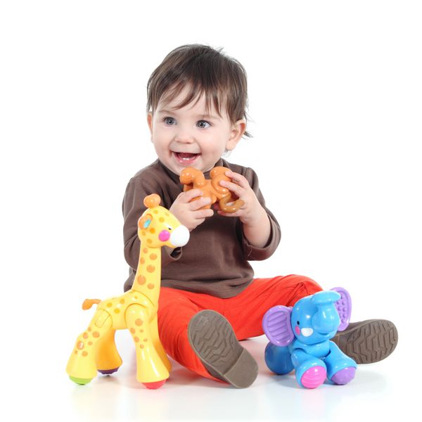 دختر بچه کوچک زیبا که با اسباب بازی های حیوانات جدا شده روی پس زمینه سفید بازی می کند