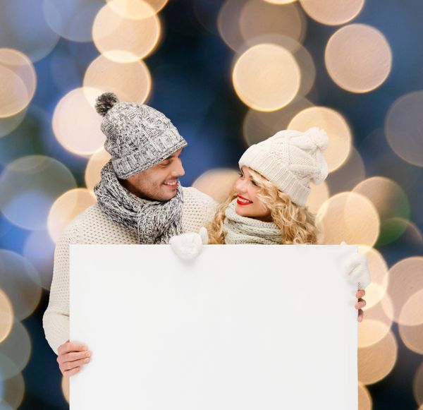 کریسمس کریسمس مردم تبلیغات زوج مفهوم فروش - زن و مرد شاد در لباس های زمستانی با تخته سفید خالی