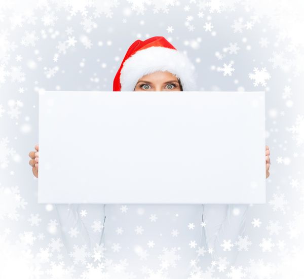 کریسمس کریسمس مردم زمستان تبلیغات و مفهوم فروش - زن متعجب با کلاه کمکی بابا نوئل با تخته سفید خالی