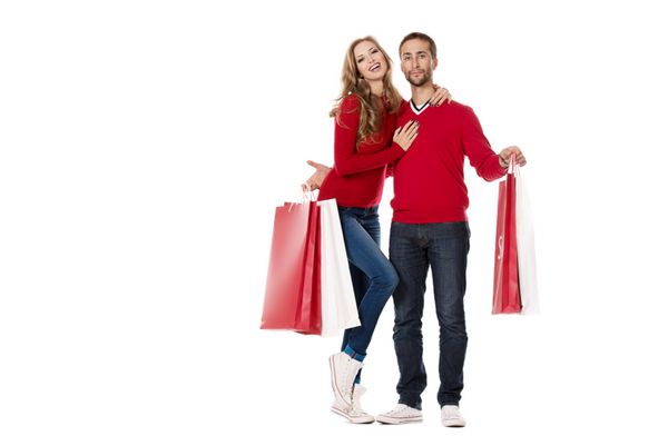زوج جوان شادی که با تعداد زیادی کیسه خرید ایستاده اند فروش جدا شده روی سفید