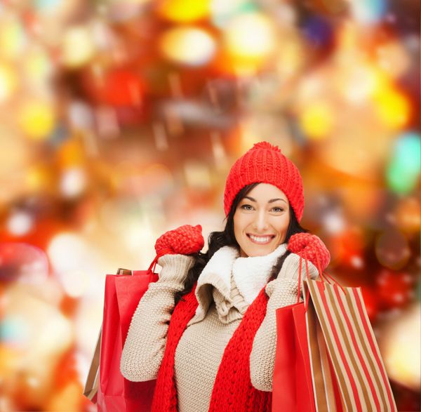 مفهوم خرده فروشی و فروش - زن شاد در لباس های زمستانی با کیسه های خرید
