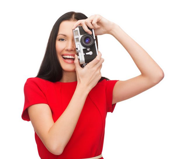 فناوری مدرن و مفهوم مردم - زن خندان با لباس های غیررسمی در حال عکس گرفتن با دوربین فیلم قدیمی
