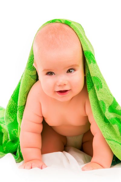 کودک کوچک شاد در حوله سبز در پس زمینه سفید