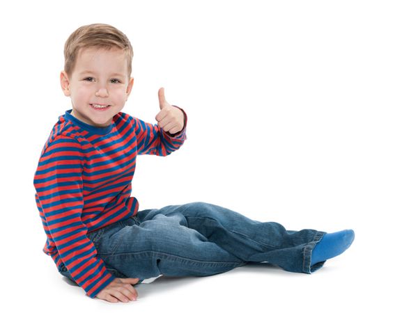 پسر بچه پیش دبستانی خندان شست خود را در پس زمینه سفید بالا گرفته است