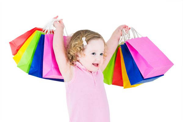 دختر کوچولوی شایان ستایش با موهای مجعد که لباس صورتی پوشیده است پس از فروش و خرید پیشنهاد ویژه خوشحال است که کیف های رنگارنگ خود را نشان می دهد