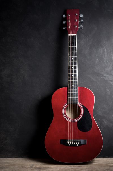 عکاسی از طبیعت بی جان گیتار آکوستیک قدیمی در پس زمینه تیره