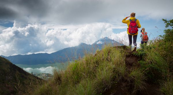 کوهنوردان با کوله پشتی در روزهای آفتابی در بالای کوه استراحت می کنند