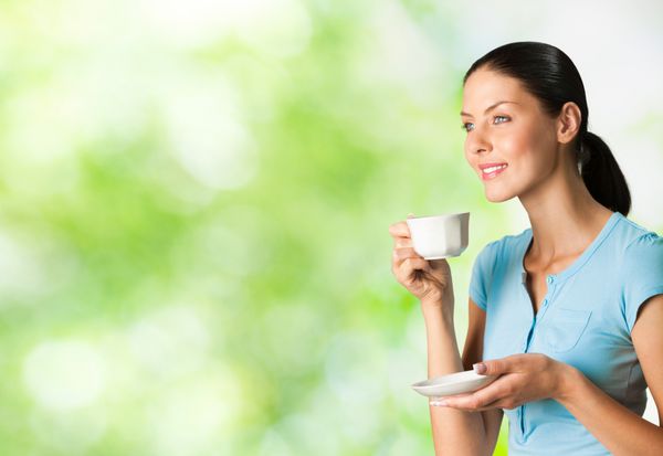 زن جوان شاد و خندان در حال نوشیدن قهوه در فضای باز می توانید از قسمت چپ برای شعار متن بزرگ یا بنر استفاده کنید