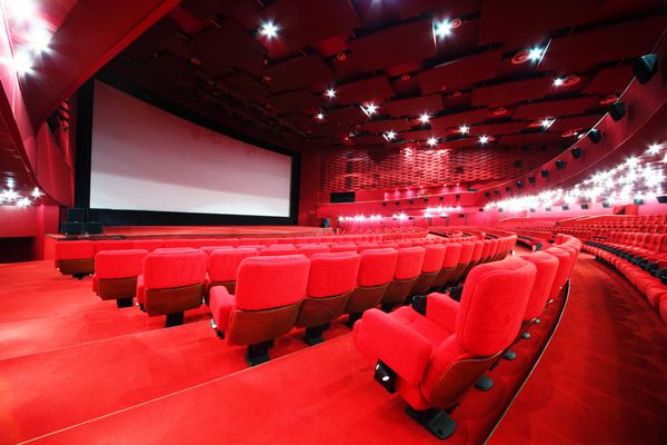 نمایی از پله ها روی صفحه و ردیف صندلی های قرمز راحت در سینمای اتاق قرمز روشن