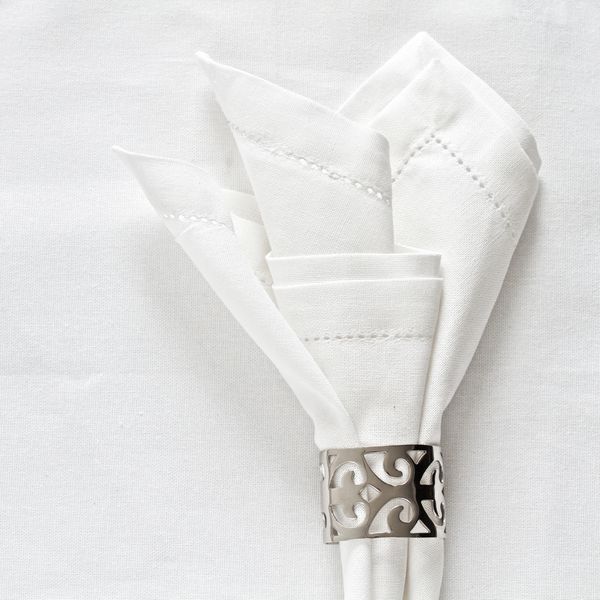 دستمال کاغذی سفید و حلقه دستمال نقره ای به عنوان چیدمان میز